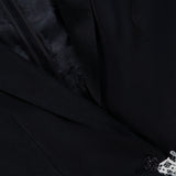 Close-up of the ALICE + OLIVIA Breann Cutaway Lace Long Fitted Blazer in black, featuring decorative cutwork lace trim by the button and a partially visible inner lining accentuating its sculpted silhouette.
