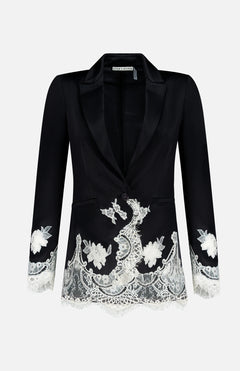 The Breann Cutaway Lace Long Fitted Blazer by ALICE + OLIVIA features a sculpted silhouette with white floral lace trim on the cuffs and hem, single button closure, and peak lapels, shown on a plain white background.
