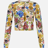 The Carson Floral Printed Cardigan by ALICE + OLIVIA is a long-sleeve, cropped top adorned with a vibrant multicolor floral pattern—blue, yellow, red, and green flowers on a white background—making it the perfect piece for embracing vintage style and adding a touch of fall florals to your wardrobe.