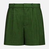 The ALICE + OLIVIA Conry Relaxed Long Pleated Short features a dark green hue, tailored fit with belt loops, front pleats, and a fitted waistband. Crafted from linen for a refined yet relaxed silhouette, these shorts are displayed against a plain white background.
