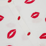 The Daroda Lip Cardigan Sweater by ALICE + OLIVIA is a cropped white knit with embroidered lips prints and red lips-shaped buttons on the front.