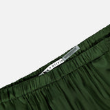Close-up of the waistband of dark green, silky Declan Pull On Genie Pant by ALICE + OLIVIA, featuring a white label with the brand name against a plain background.