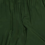 The ALICE + OLIVIA Declan Pull On Genie Pant is shown here in dark green satin with an elastic waistband. The silky charmeuse fabric has a smooth, slightly shiny finish, featuring natural folds and creases from the waist to mid-thigh.
