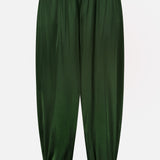 The Declan Pull On Genie Pant by ALICE + OLIVIA is crafted from exceptionally smooth and shiny dark green satin charmeuse, featuring an elastic waistband and elastic cuffs for a classic genie pant silhouette. Shown against a plain white background.