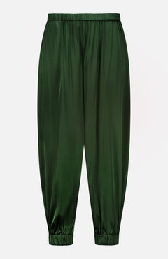 The Declan Pull On Genie Pant by ALICE + OLIVIA is crafted from exceptionally smooth and shiny dark green satin charmeuse, featuring an elastic waistband and elastic cuffs for a classic genie pant silhouette. Shown against a plain white background.