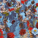 The Delora Folded Turtleneck Mini Dress by ALICE + OLIVIA features a blue floral pattern with red, white, yellow, and blue flowers, green and brown leaves, and a subtle lace-like background for a striking look.