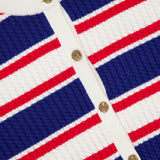 Close-up of the Dollie Striped Cable Cardigan by ALICE + OLIVIA featuring horizontal blue, red, and white stripes, white trim, and statement gold buttons down the front.