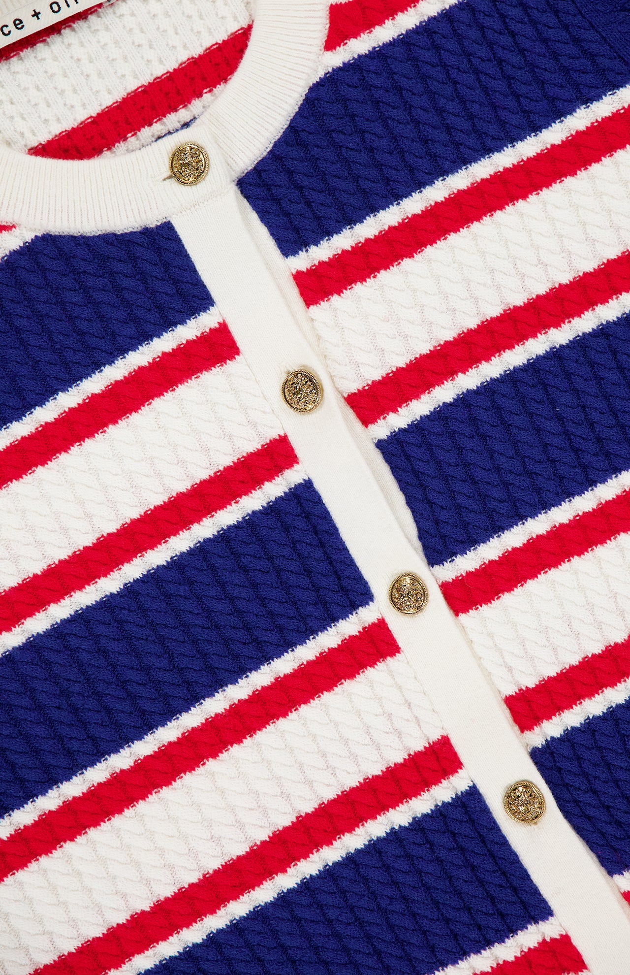 Close-up of the Dollie Striped Cable Cardigan by ALICE + OLIVIA featuring horizontal blue, red, and white stripes, white trim, and statement gold buttons down the front.