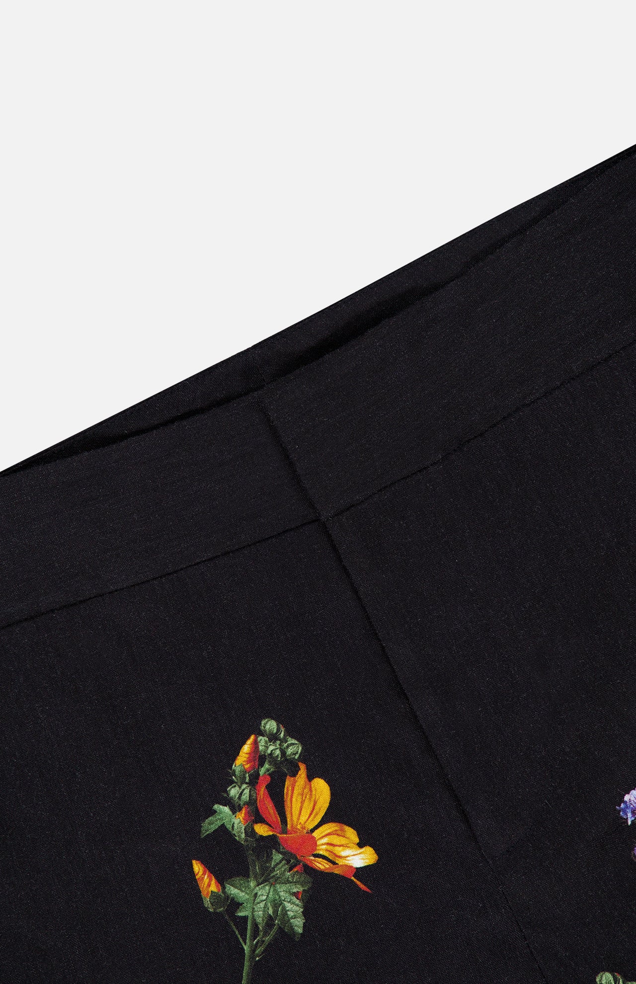 Close-up of a black fabric with a dark floral pattern featuring yellow, orange, and purple flowers and green leaves against a plain background—ideal for crafting the Dylan High Rise Wide Leg Pant from ALICE + OLIVIA for vibrant style.