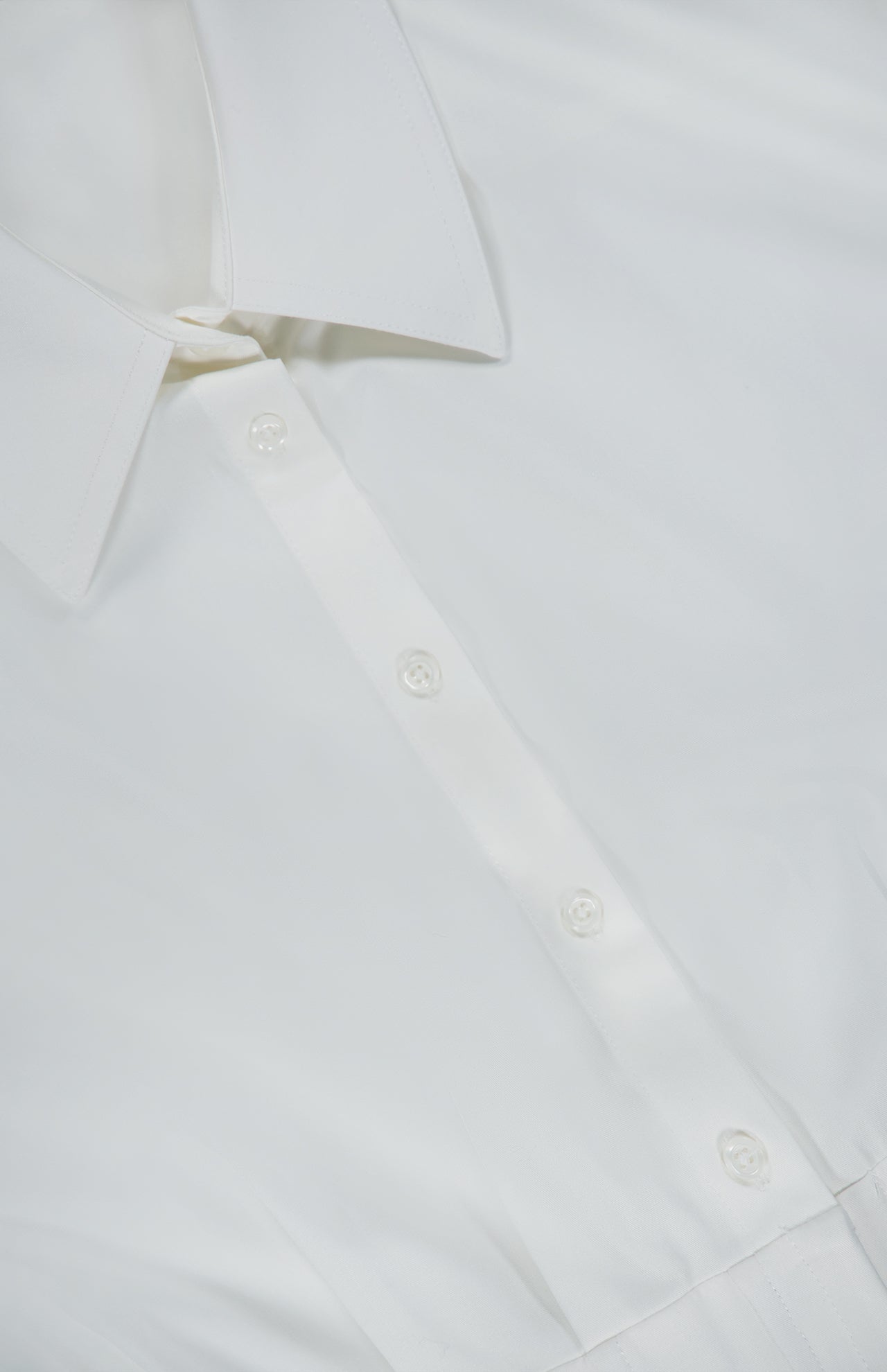 Close-up of the Edle Gathered Corset Button Down Top by ALICE + OLIVIA in off-white, highlighting its collar, buttons, and upper front. The smooth, crisp fabric is accentuated by subtle corset detailing that lends a sophisticated touch to this classic blouse design.