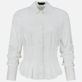 The Edle Gathered Corset Button Down Top by ALICE + OLIVIA features off-white long sleeves, a pointed collar, ruched detailing on the sleeves, and a structured waist that flares into a peplum hem. It is displayed against a plain white background.