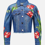 The Elijah Embellished Applique Cropped Denim Jacket by ALICE + OLIVIA is a blue cropped denim jacket with silver buttons, featuring a cropped silhouette and vivid red and white tulip flower embroidered floral appliques on the front, sleeves, and left shoulder.