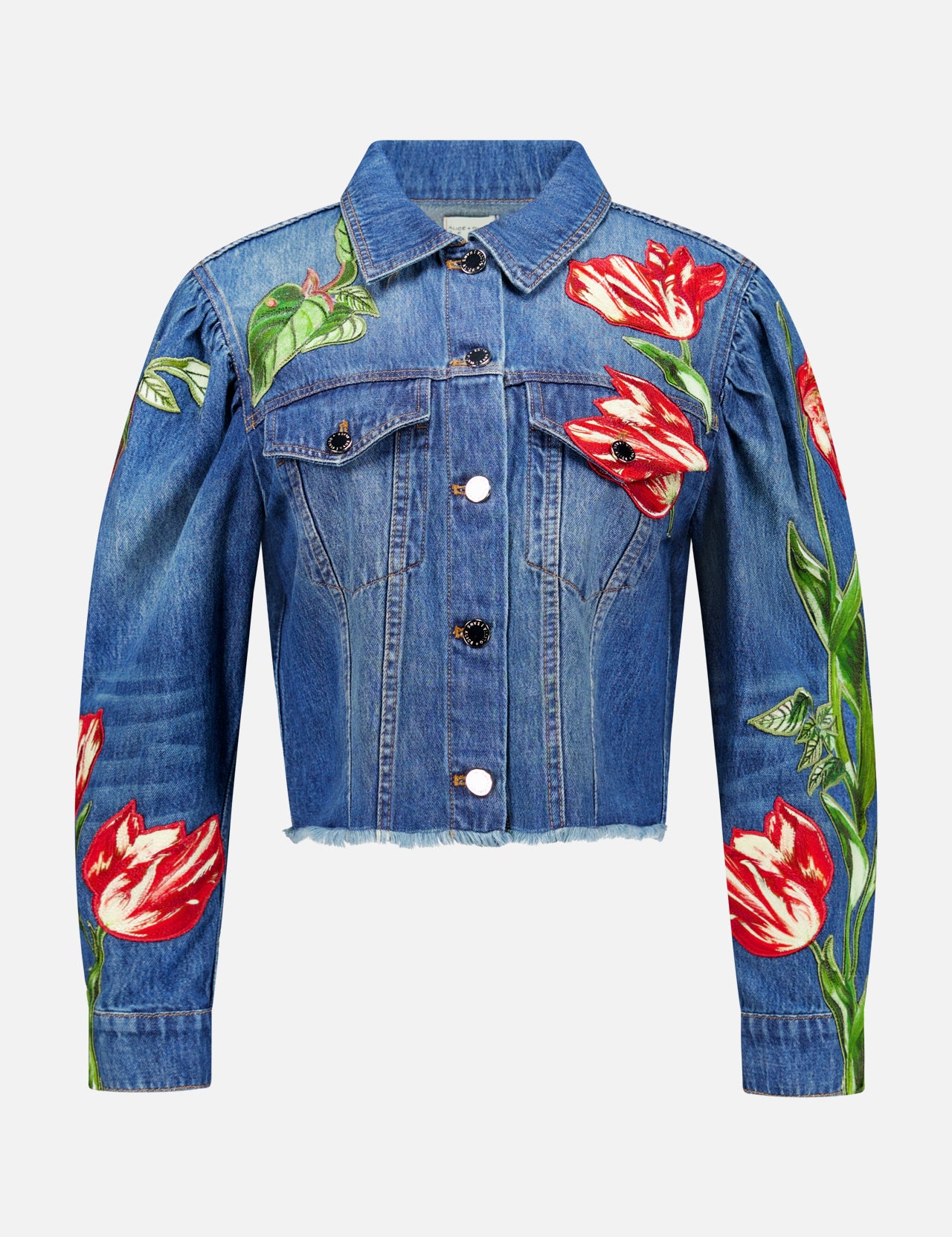 The Elijah Embellished Applique Cropped Denim Jacket by ALICE + OLIVIA is a blue cropped denim jacket with silver buttons, featuring a cropped silhouette and vivid red and white tulip flower embroidered floral appliques on the front, sleeves, and left shoulder.
