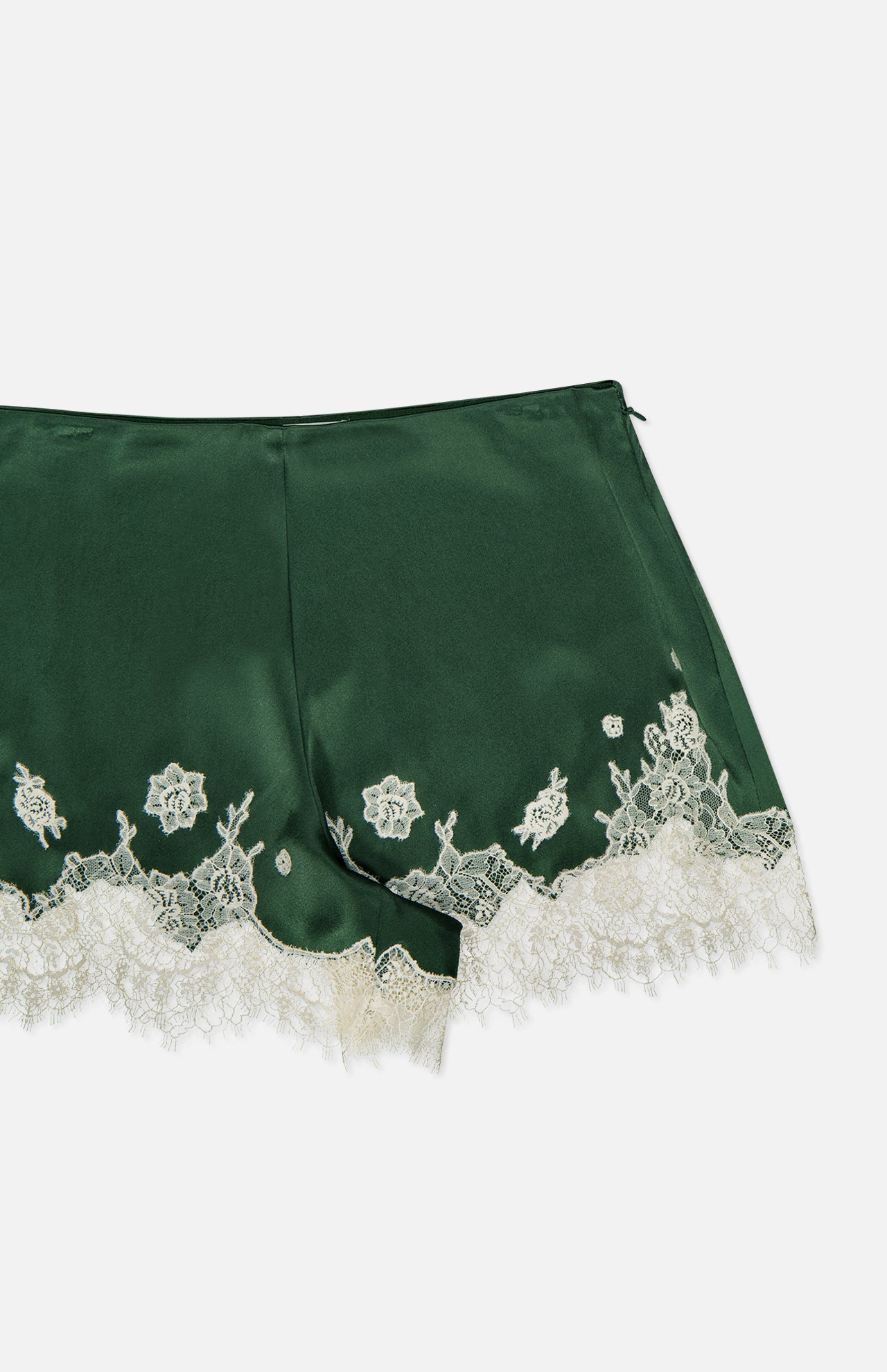 The Elissa Cutaway Lace Short by ALICE + OLIVIA features a dark green satin construction with elegant white bloom cutwork lace trim and detailing along the hem, perfect for channeling a chic summer Hamptons vibe—shown here against a white background.