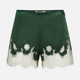 The Elissa Cutaway Lace Short by ALICE + OLIVIA features dark green satin with delicate white lace trim and floral embroidery along the hem, perfect for a summer-in-the-Hamptons look, displayed against a plain white background.