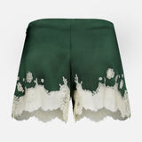 Elissa Cutaway Lace Short by ALICE + OLIVIA, featuring dark green satin and elegant bloom cutwork lace trim along the hem, displayed against a plain white background.