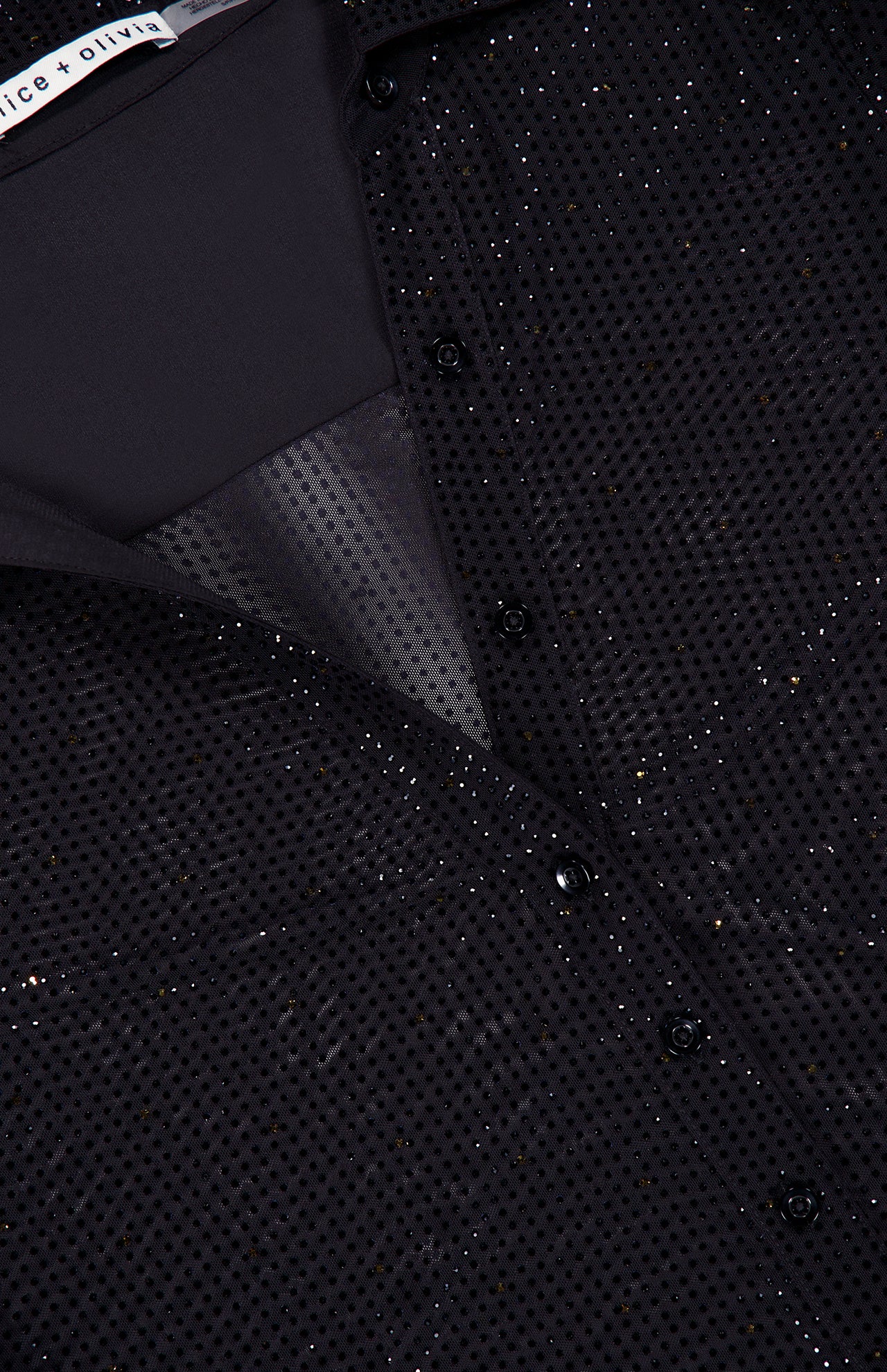 Close-up of the Freya Embell Fitted Nipped Waist Shirt by ALICE + OLIVIA: a black blouse with subtle shimmer, small perforations, and elegant collar and button details.
