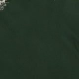 A cream-colored lace trim adorns the top edge of a deep green background, evoking the elegant details of the ALICE + OLIVIA Julietta Cutaway Lace Trim Slip Dress. The remainder of the image showcases a smooth, solid dark green surface that mirrors the fabric of this sophisticated dress.