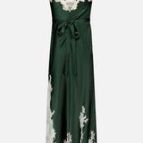 The Julietta Cutaway Lace Trim Slip Dress by ALICE + OLIVIA features a dark green satin fabric with delicate ivory lace along the neckline and hem, spaghetti straps, a V-neckline, and a waist tie. This elegant midi dress showcases a long, flowy silhouette enhanced by its cutaway lace detailing.