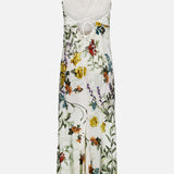 ALICE + OLIVIA’s Montana Slim Strappy Back Maxi Dress is a white satin cocktail dress with thin straps, an open back with tie detail, and a colorful floral print featuring yellow, red, and purple flowers with green leaves.