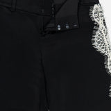 Close-up of Olivia Pant with Cutaway Lace Godet by ALICE + OLIVIA, featuring an open waistband with hook-and-bar closure, inner lining, and cutaway lace godet detail at the right thigh.