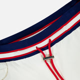 Close-up of the ALICE + OLIVIA Olympia Mr Baggy Cargo Pant With Side Stripe, featuring a blue, red, and white striped elastic waistband with red drawstrings and a silver metal clasp.