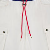 The Olympia Mr Baggy Cargo Pant With Side Stripe by ALICE + OLIVIA features white cargo pants with a blue, white, and red striped elastic waistband, a red drawstring with metal tips, and sporty metal-detailed cargo pockets.