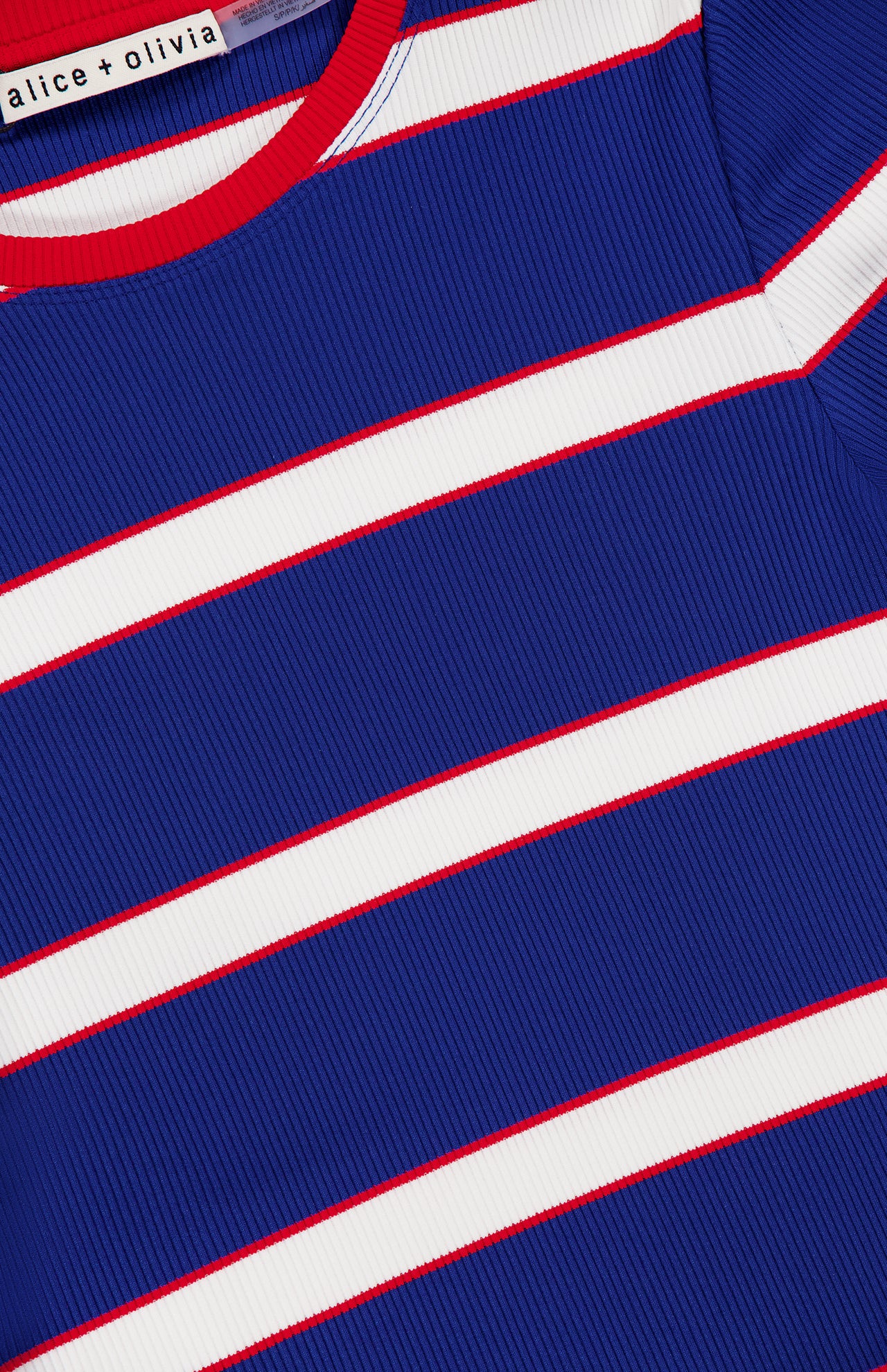 Close-up of the ALICE + OLIVIA Onie Baby Ringer T-shirt, showcasing ribbed fabric with blue, white, and red stripes, a red neckline, and a visible brand label—this vintage-inspired top adds playful charm to any baby wardrobe.