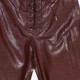 Close-up of the Ravyn Vegan Leather Lace Up Bootcut Pant by ALICE + OLIVIA, featuring a burgundy, low-rise silhouette with a lace-up front and gold-tipped drawstrings.