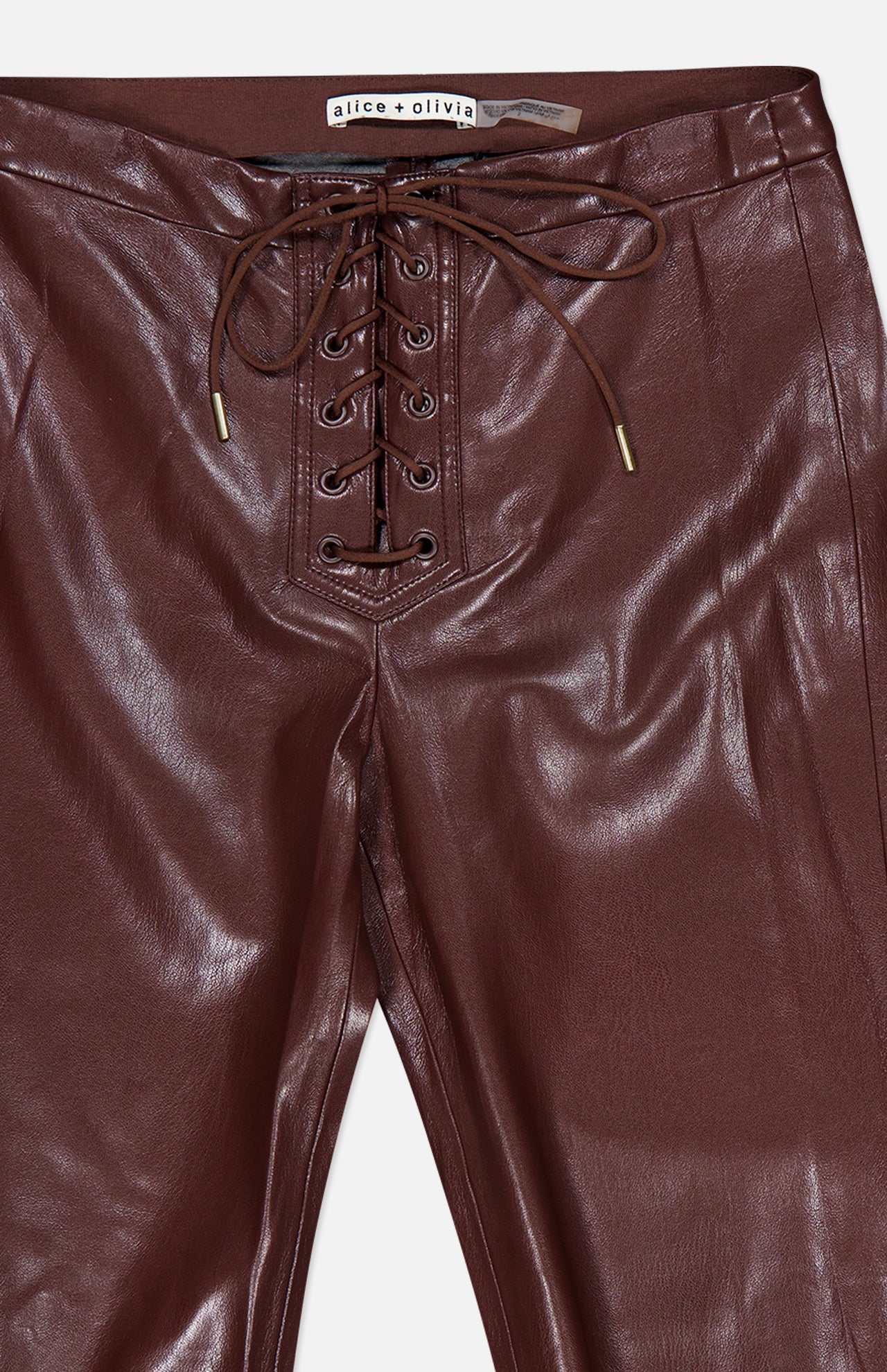 Close-up of the Ravyn Vegan Leather Lace Up Bootcut Pant by ALICE + OLIVIA, featuring a burgundy, low-rise silhouette with a lace-up front and gold-tipped drawstrings.