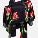The Rita Off The Shoulder Draped Top with Scarf by ALICE + OLIVIA pairs a cropped black off-the-shoulder top with a luxe black silk charmeuse scarf adorned with bold red and white tulip prints and green leaves, artfully draped to highlight the striking floral pattern.