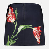 The Rubi Low Rise Floral Skirt by ALICE + OLIVIA is a black mini skirt adorned with a striking red and white tulip print and green stems, finished with a visible back zipper. This romantic piece seamlessly blends elegance with a playful flair.