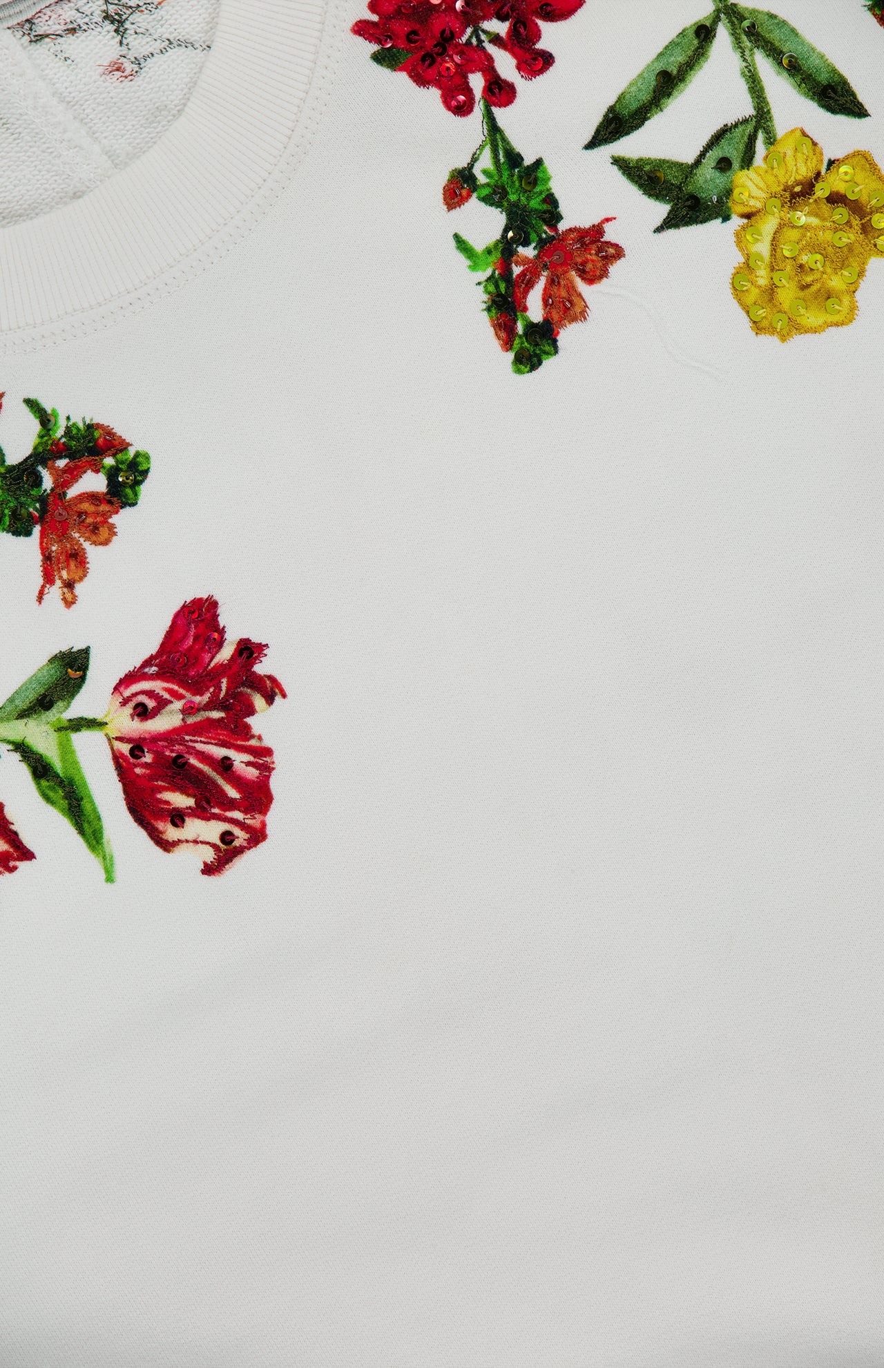 The Russell Embellished Relaxed Crewneck Sweatshirt by ALICE + OLIVIA features a cropped white design adorned with colorful embroidered flowers—red, yellow, and orange blooms with green leaves—arranged near the collar, and finished with delicate sequin embroidery for extra sparkle.