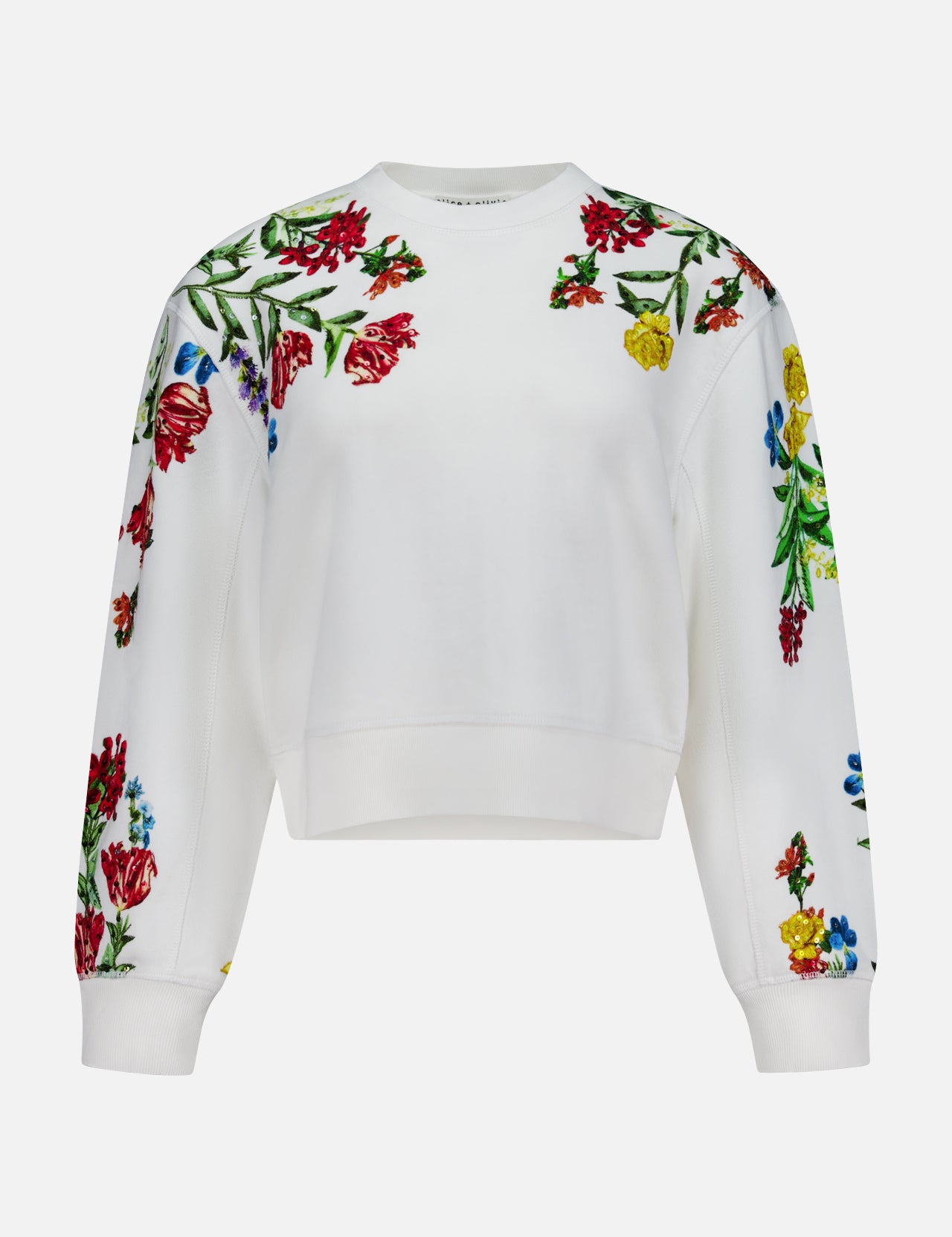 The Russell Embellished Relaxed Crewneck Sweatshirt by ALICE + OLIVIA is a white, cropped-fit sweatshirt adorned with colorful floral embroidery in shades of red, yellow, and blue with green leaves on the shoulders, sleeves, and upper chest.