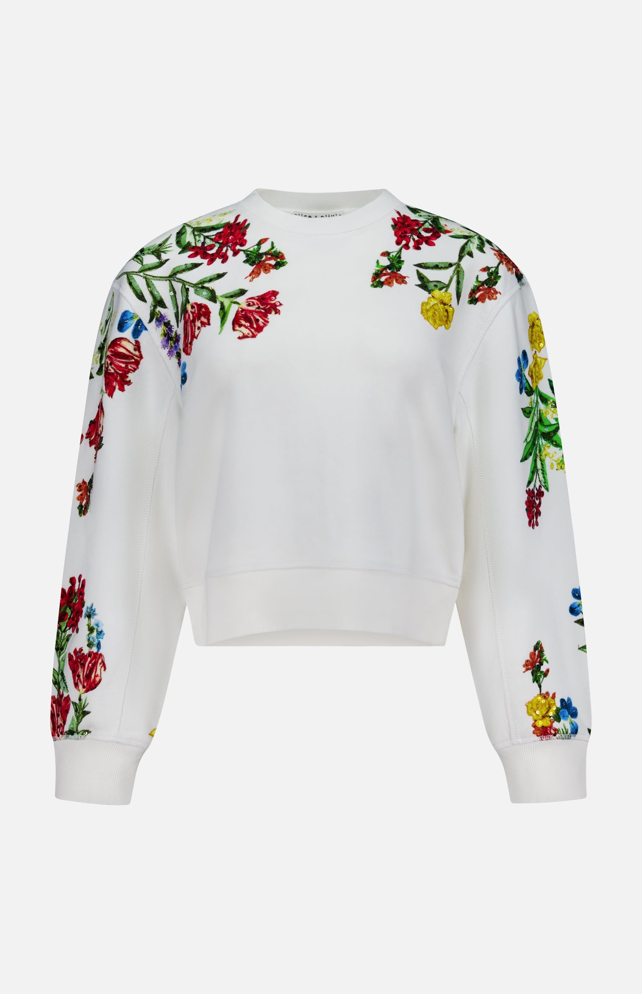 The Russell Embellished Relaxed Crewneck Sweatshirt by ALICE + OLIVIA is a white, cropped-fit sweatshirt adorned with colorful floral embroidery in shades of red, yellow, and blue with green leaves on the shoulders, sleeves, and upper chest.