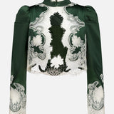 The Thomasina Puff Sleeve Cropped Jacket by ALICE + OLIVIA is a dark green, long-sleeve jacket featuring structured shoulders, puff sleeves, a high neck, floral patterns, and white bloom cutwork lace detailing in a cropped silhouette. The jacket is displayed against a plain white background.