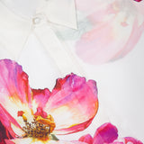Close-up of the ALICE + OLIVIA Willa Hidden Placket Silk Top, a white blouse with bright pink and red floral prints and green leaves—ideal for adding a designer touch to your outfit.