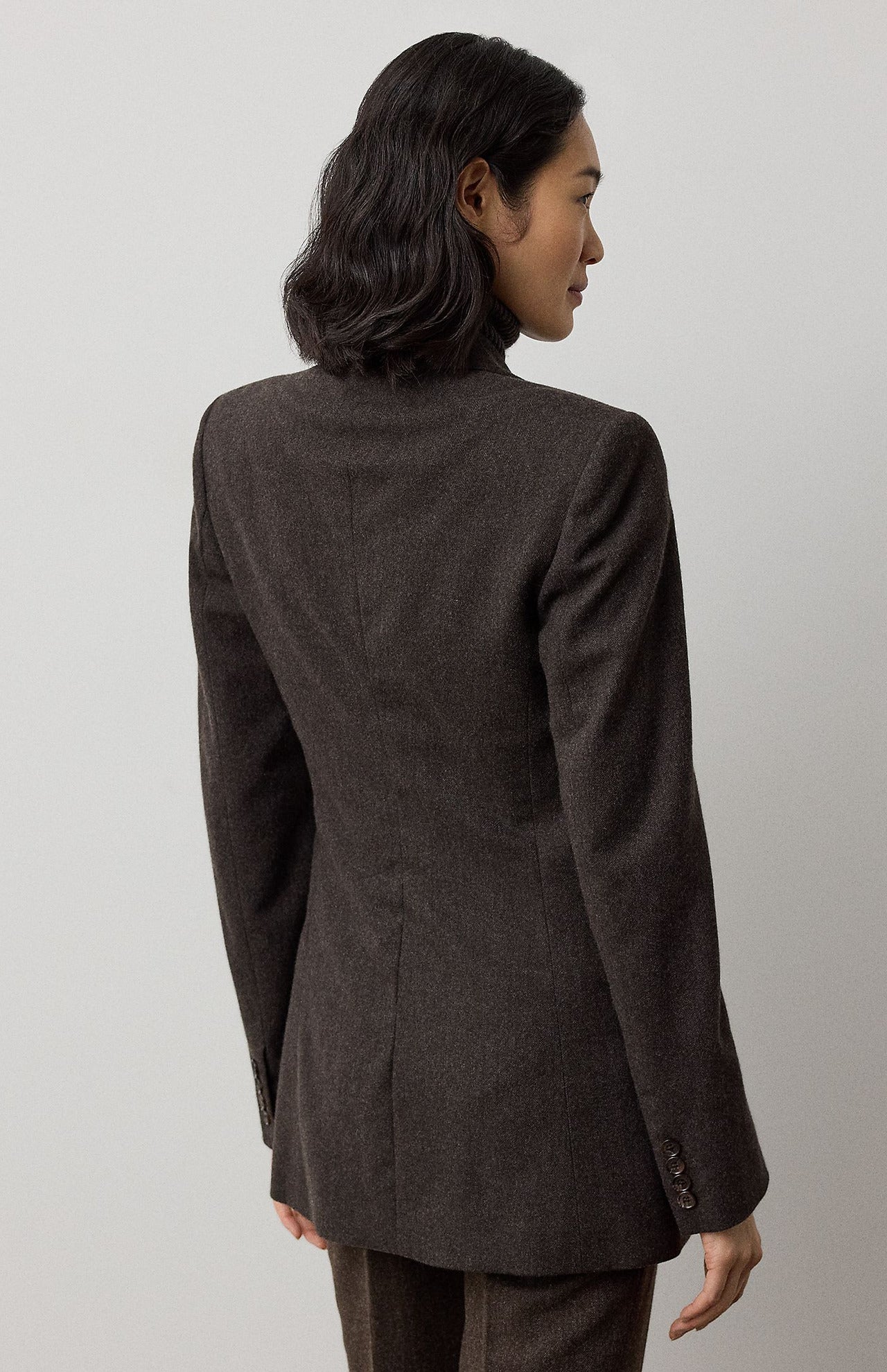 A person viewed from behind wearing a RALPH LAUREN COLLECTION Mini Herringbone Blazer in a tailored dark brown wool with a subtle mini-herringbone pattern.