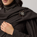 A dark gray RALPH LAUREN COLLECTION Mini Herringbone Blazer worn with a matching detachable scarf pinned with a circular silver and tortoiseshell crest brooch.