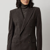A woman wearing a dark brown Mini Herringbone Blazer by Ralph Lauren Collection over a matching turtleneck sweater with a detachable scarf.