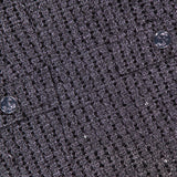 Close-up of the Empire Sparkle Tweed Mini Dress by AMANDA UPRICHARD, featuring textured dark gray fabric with a grid pattern, silver shimmer, and two buttons—ideal for an elegant cocktail look.