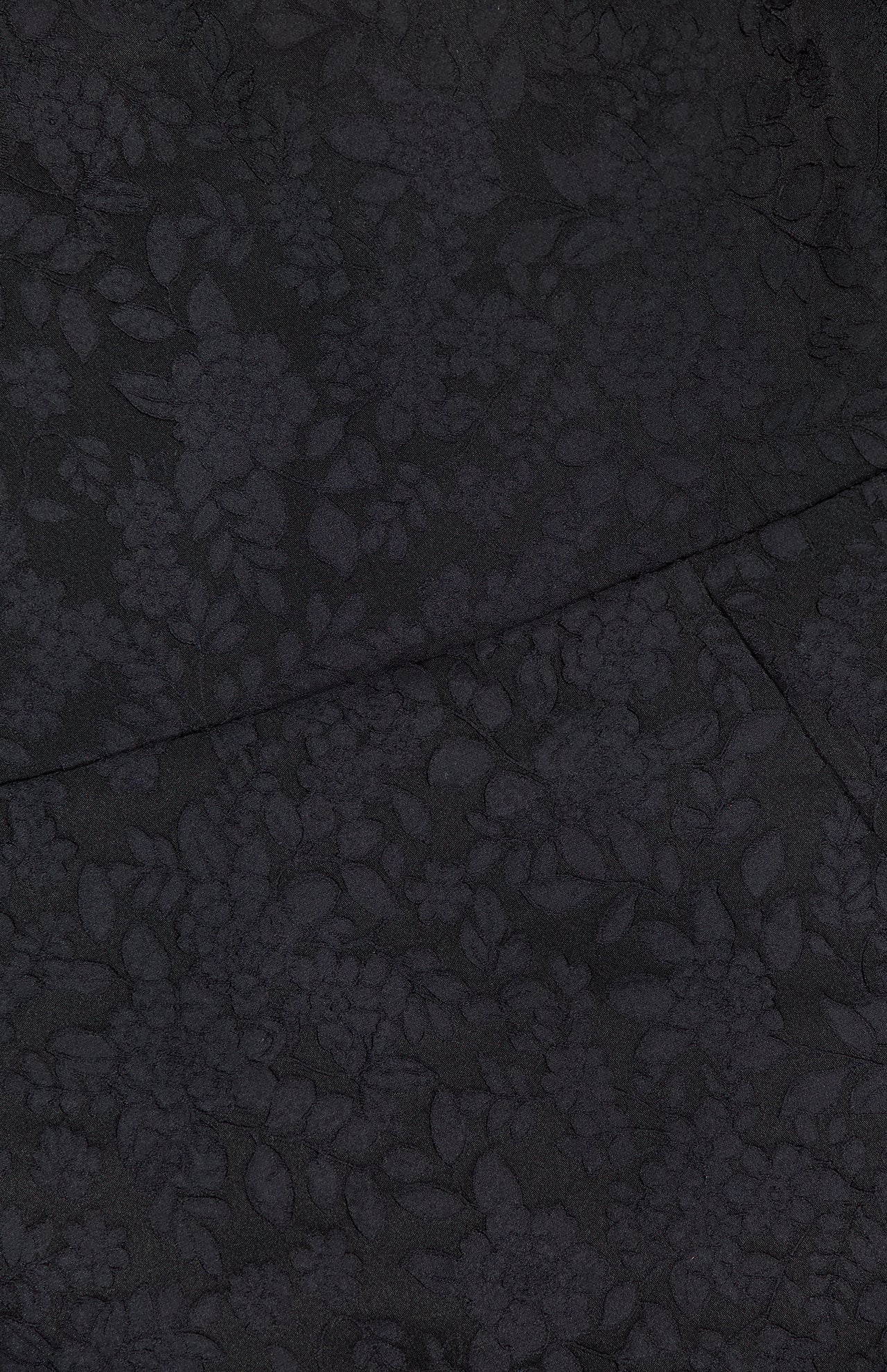 Close-up of the AMANDA UPRICHARD Rhonda Floral Print Romper's dark fabric, featuring a subtle raised floral pattern and overlapping seams—ideal for adding elegant texture to your look.