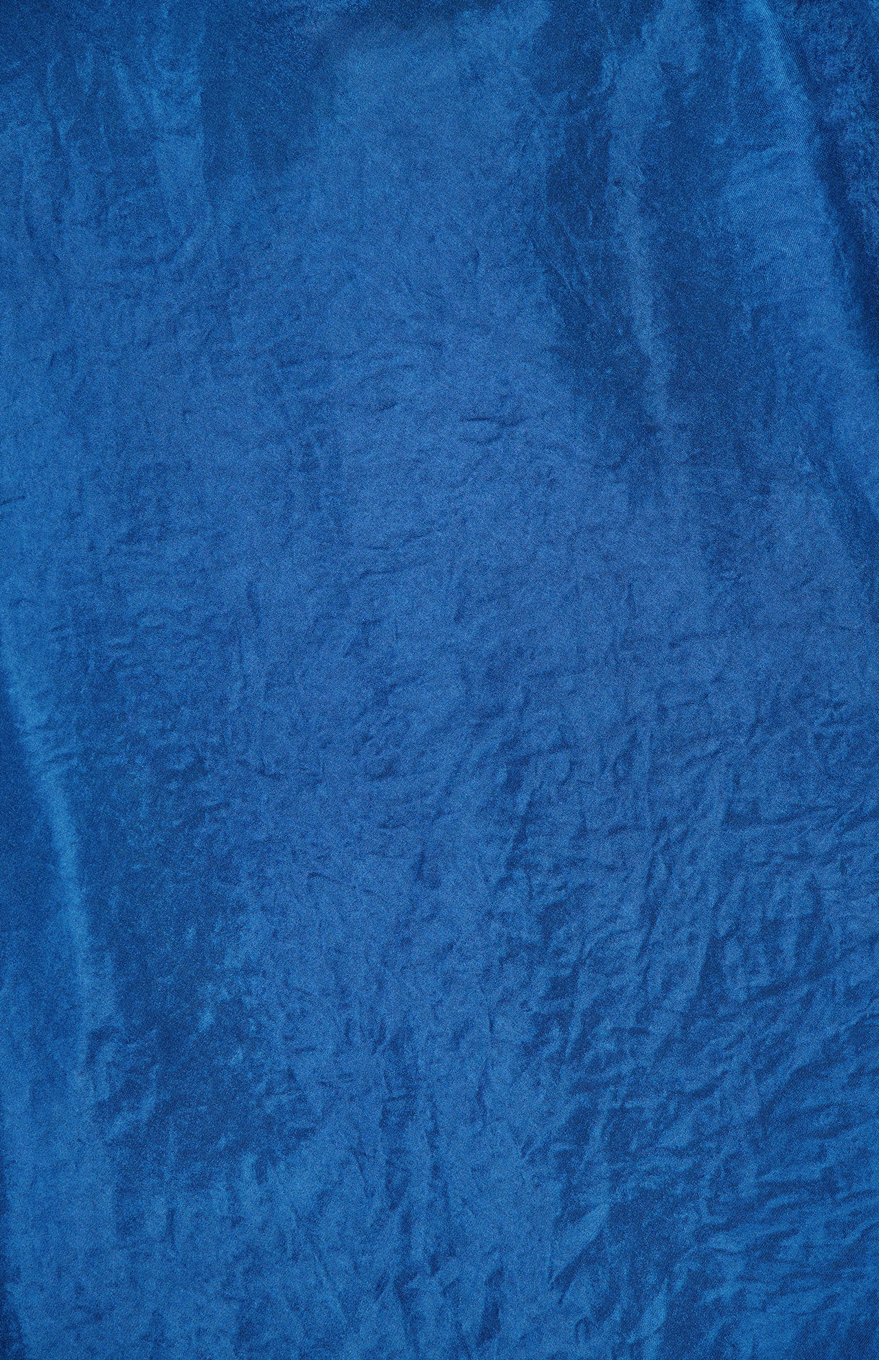 A close-up of blue velvet fabric with a soft, slightly crushed texture and subtle creases, capturing the luxe vibe of the Arielle Halter Top by AMANDA UPRICHARD—ideal for your next vacation look.