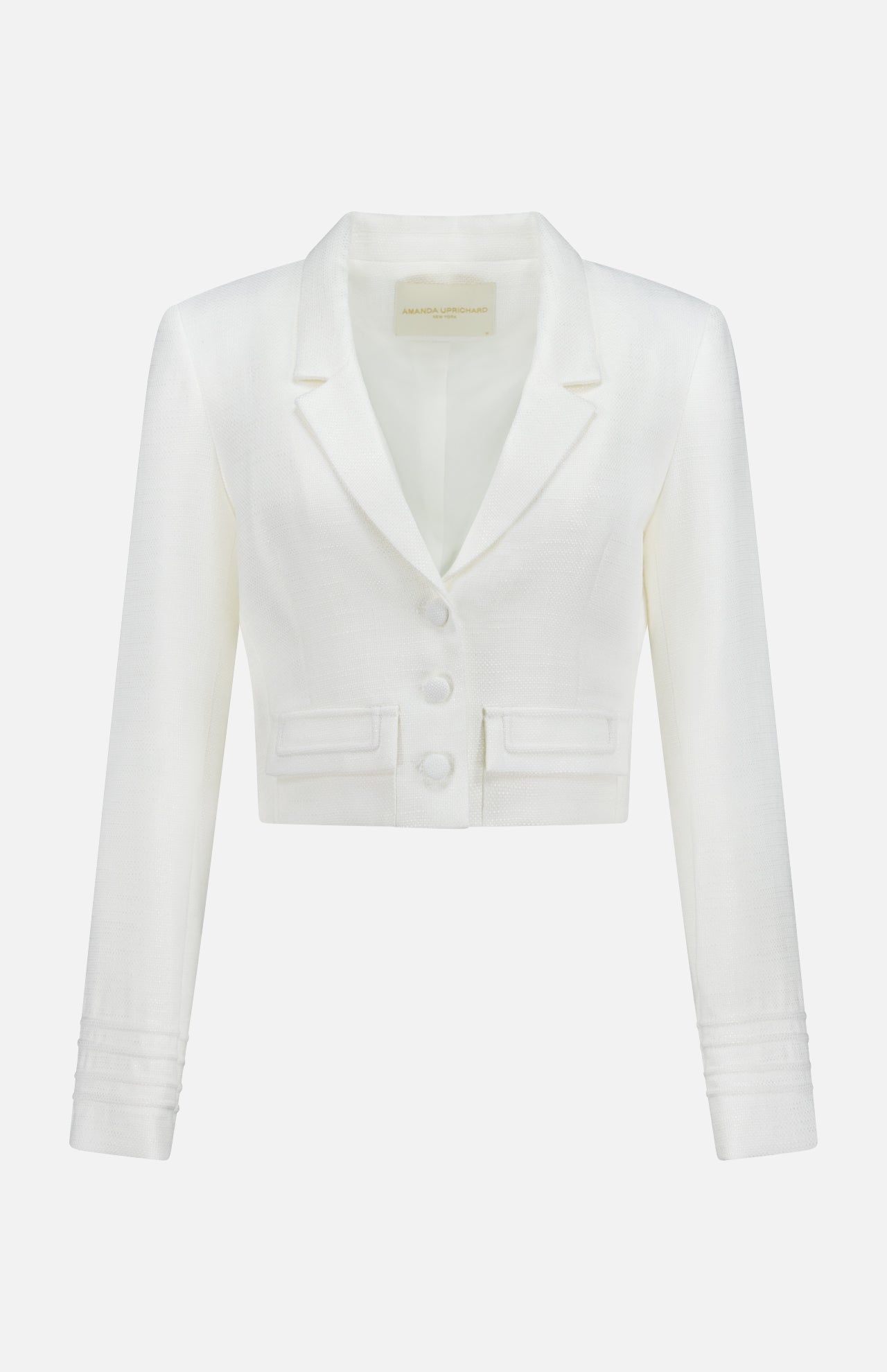 The Courtney Cropped Jacket by AMANDA UPRICHARD is a white tailored blazer with long sleeves, notched lapels, three front buttons, and two small pockets, shown against a plain white background.