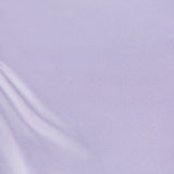 The smooth lavender-colored fabric of the Jean Ruched Knot Midi Dress by AMANDA UPRICHARD features soft folds in the lower left corner, creating gentle lines and a subtle sheen. The overall appearance evokes calm and minimalist cocktail attire, reminiscent of luxurious silk.