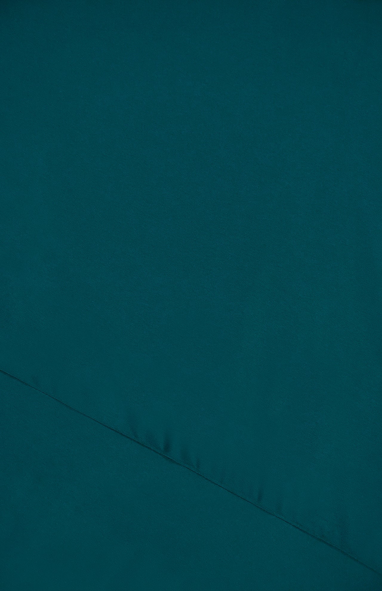 A close-up view of teal fabric from the AMANDA UPRICHARD Jeannine Maxi Dress highlights the diagonal seam, texture, and detailed stitching.