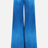 The Kordell Satin Pants by AMANDA UPRICHARD feature a high waist and wide-leg, flared silhouette in bright teal satin, adding a luxe touch to resort wear with their smooth, shiny finish against a white background.