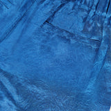 Close-up of AMANDA UPRICHARD’s Kordell Satin Pants in teal, featuring a crinkled texture, elastic waistband, and single back pocket—ideal for relaxed resort wear.