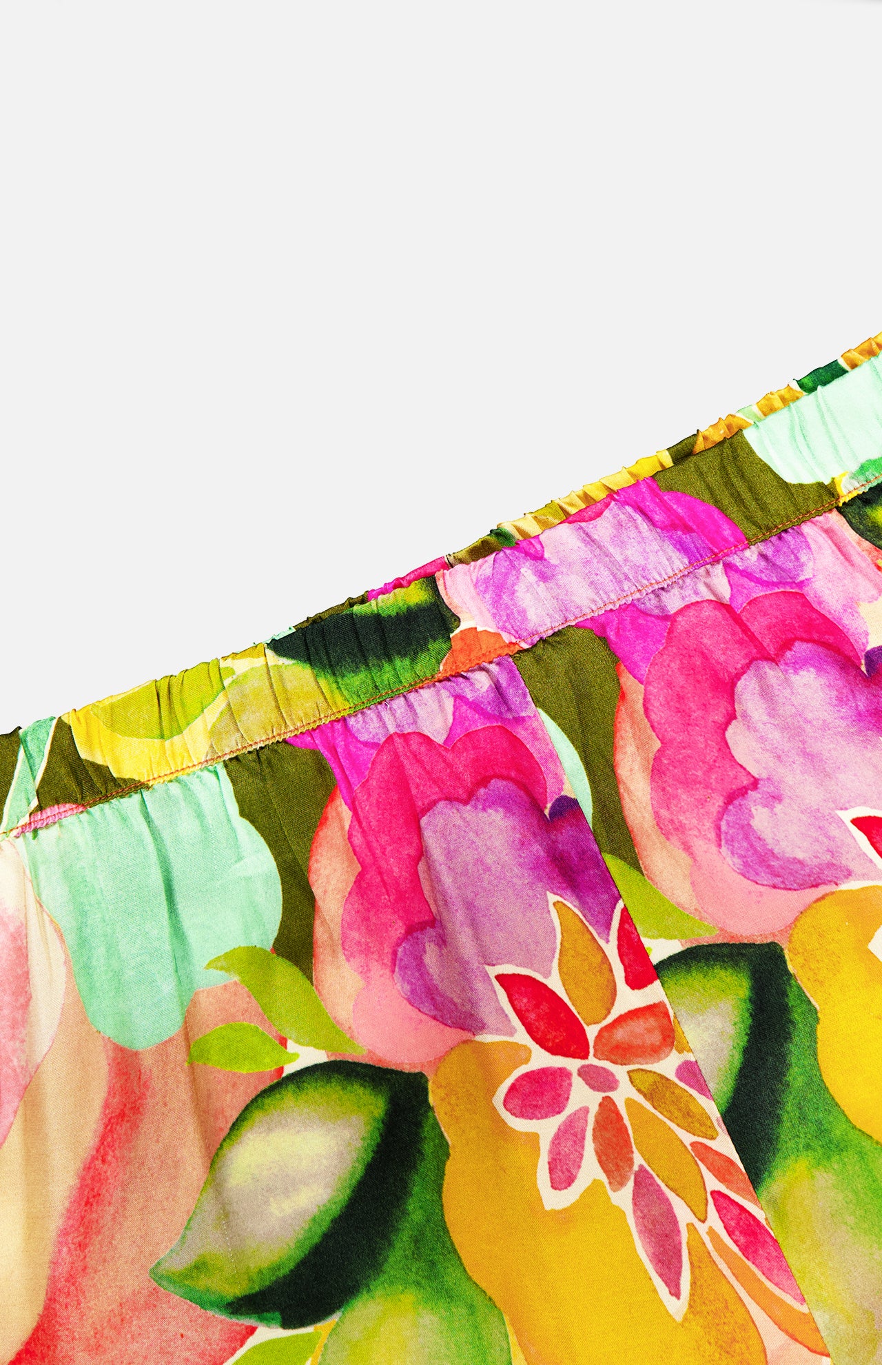 Close-up of the Mariko Wide Leg Floral Pants by AMANDA UPRICHARD, showcasing a vibrant floral print in pink, yellow, green, and red with an elastic gathered top—ideal for a relaxed wide-leg silhouette.