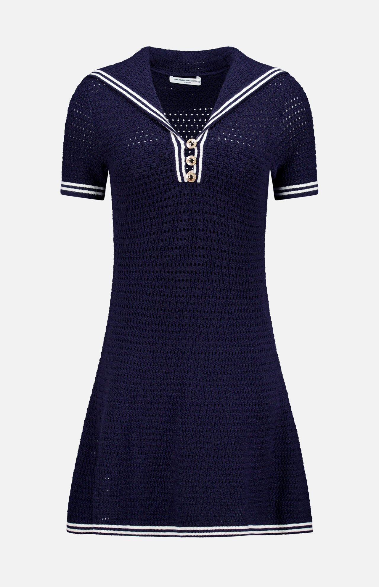 The Monique Sailor Neckline Dress by AMANDA UPRICHARD is a navy blue fit and flare mini dress with short sleeves, white stripe accents, gold front buttons, textured knit fabric, and an airy crochet pattern.